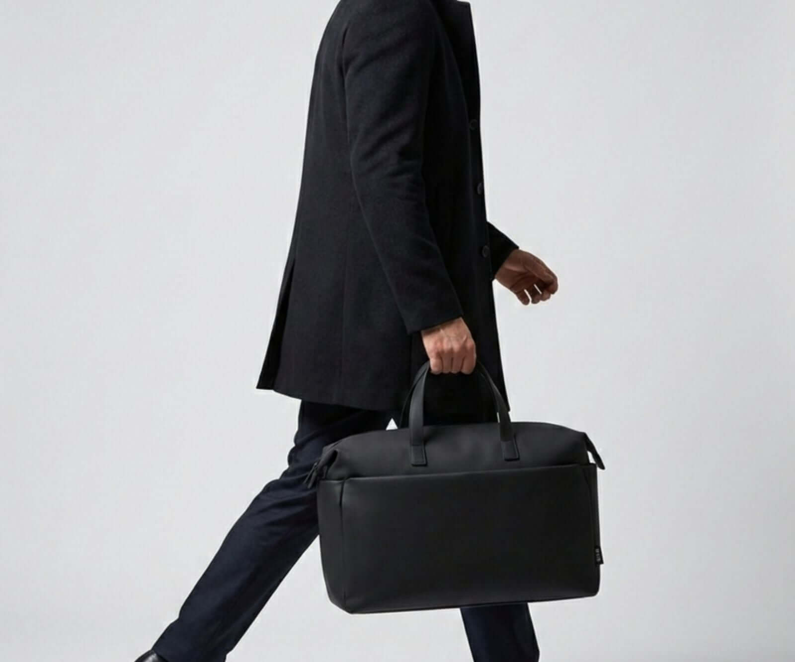 A person is holding Midnight and black weekender